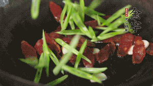 先后下香腸片、四季豆絲均勻翻炒，加適量清水燜煮一下。