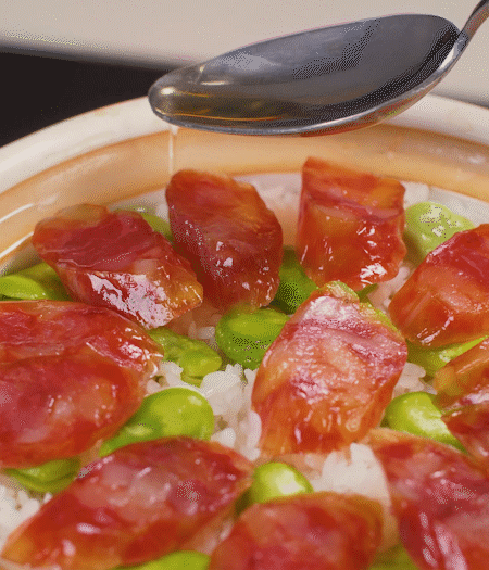 大米出現(xiàn)小孔時(shí)開(kāi)蓋放香腸，往鍋邊淋入少許油，再燜煮8~10分鐘左右。