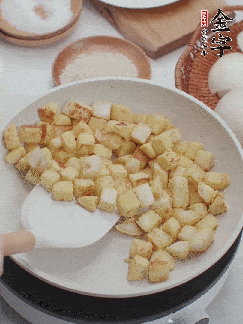 起鍋熱油，倒入饅頭丁，小火煎至蛋液凝固定型再翻面，饅頭丁部煎至金黃時盛起待用。