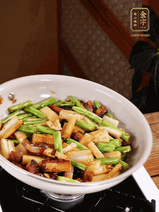 油熱下蒜末、干辣椒、醬肉煸炒出香味，依次下藕條、豆角翻炒均勻
